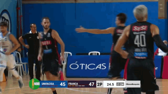 a basketball game is being played in front of a banner that says oticas
