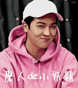 a young man wearing a pink hoodie and a white hat .