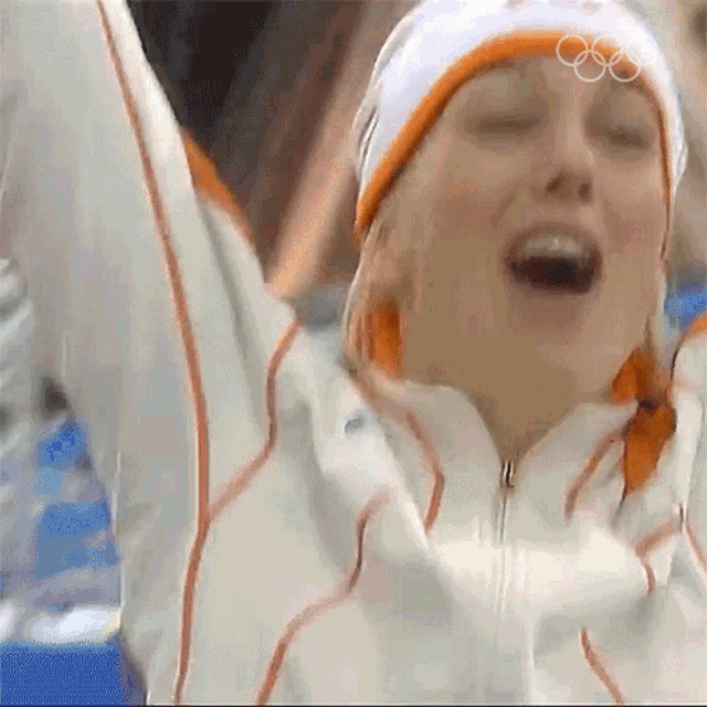 a woman wearing a hat with the olympic rings on it is celebrating