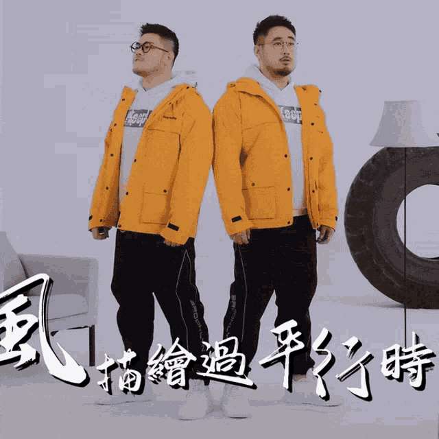 two men wearing yellow jackets are standing next to each other in front of chinese writing