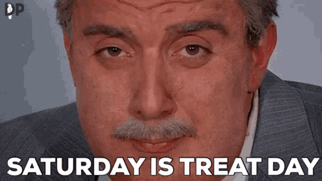 a man with a mustache is wearing a suit and says saturday is treat day .