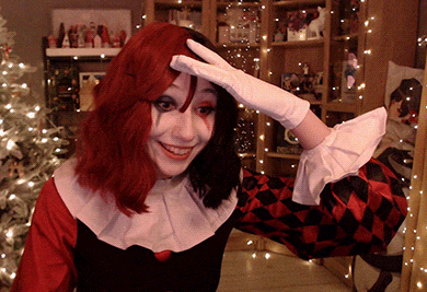 a woman in a harley quinn costume is smiling with her hand on her head