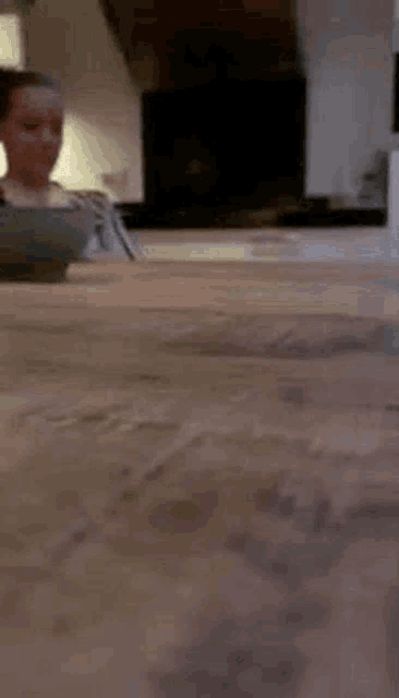 a woman is sitting at a table in a kitchen with a bowl on it .