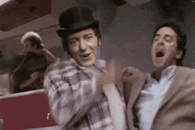 a man in a top hat is dancing with another man .