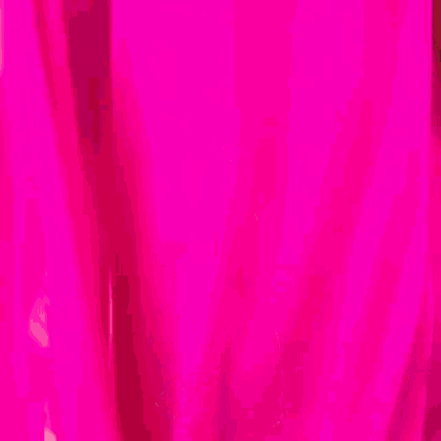 a woman in a bright pink dress is walking down a sidewalk