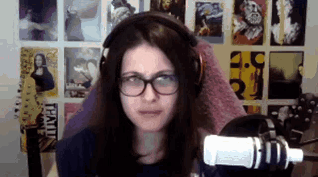 a woman wearing headphones and glasses is sitting in front of a microphone in a room .