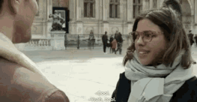 a man and a woman are talking to each other on a city street .