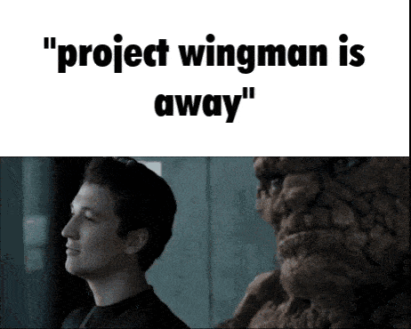 a man is standing next to a statue of a man with the words `` project wingman is away '' written on it .