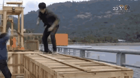 a man is jumping over a wooden crate on a bridge with the number 3 on the bottom