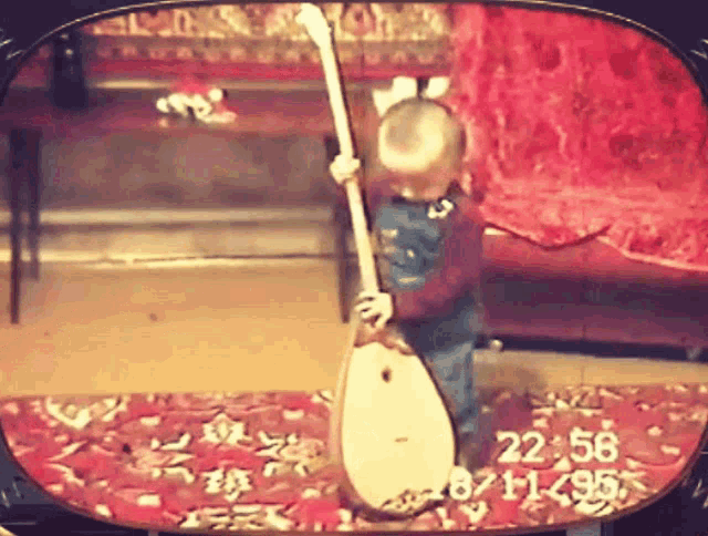 a little boy is playing a guitar in front of a screen that says 22:58