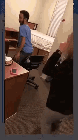 a man in a blue shirt sits on a chair in a room