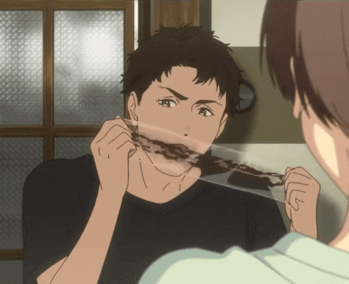a man with a piece of chocolate in his mouth looks at another man