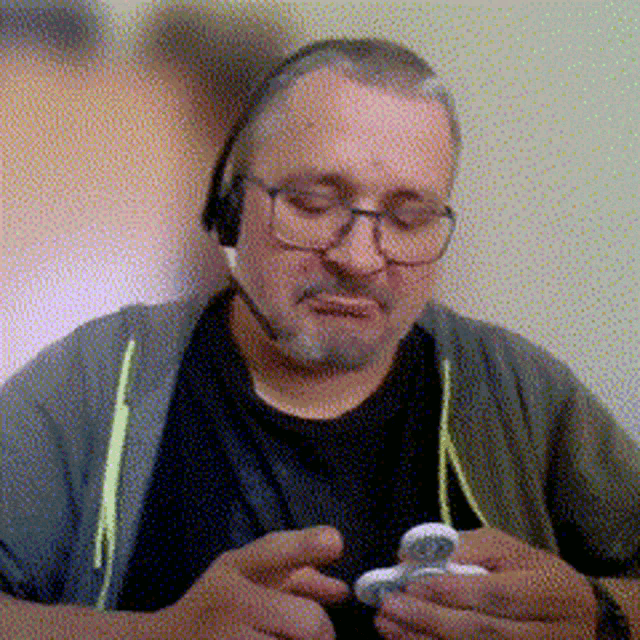 a man wearing glasses and headphones is holding a small object in his hands