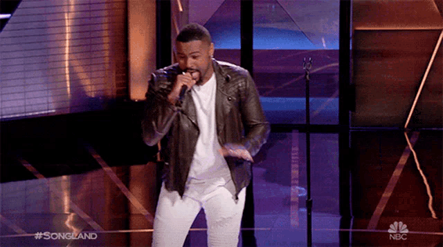 a man singing into a microphone on a stage with the words #songland on the bottom