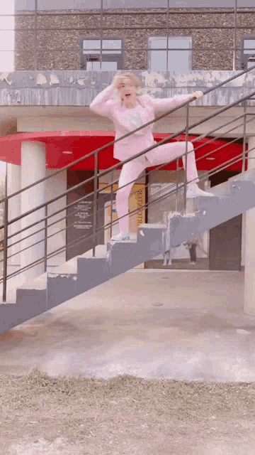 a woman in a pink suit stands on a set of stairs in front of a sign that says welcome