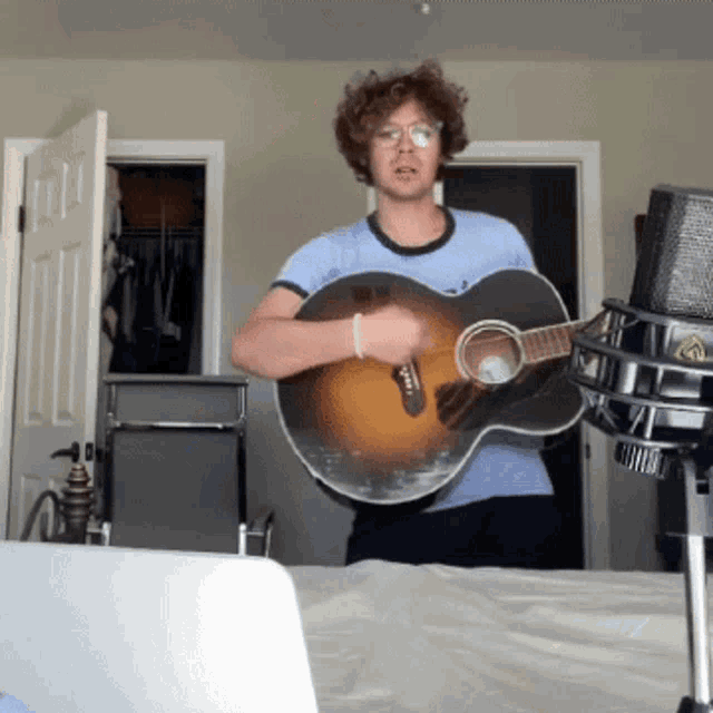 a man is holding an acoustic guitar in front of a microphone