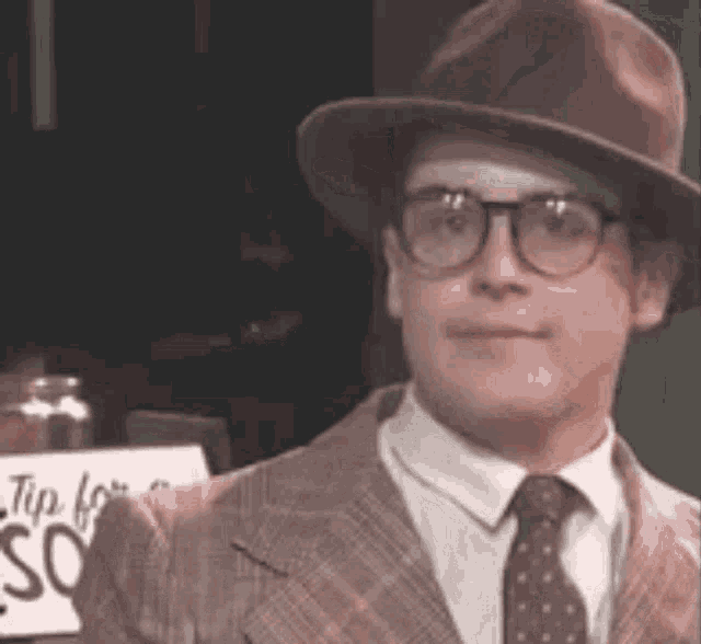 a man wearing a hat and glasses is holding a sign that says `` i 'm for so '' .