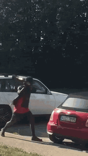 a man standing next to a red car and a white car with a license plate that says lion on it