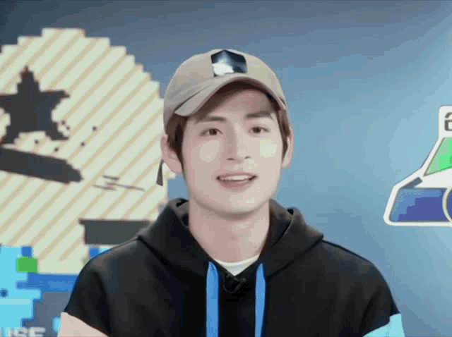 a young man wearing a baseball cap and a hoodie is smiling for the camera