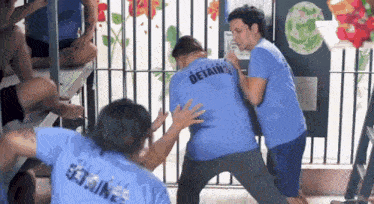 a man wearing a blue shirt that says detain on it