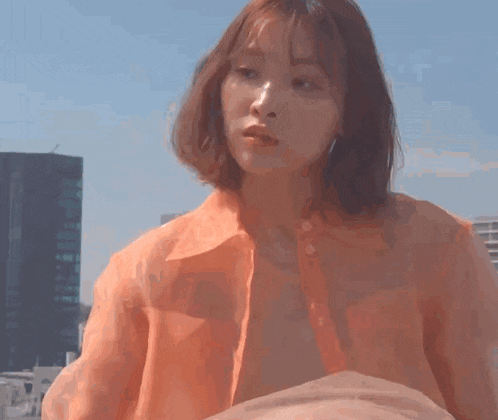 a woman wearing an orange shirt is looking at the camera