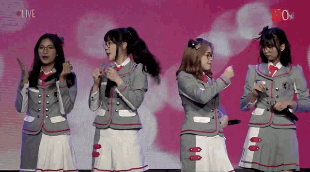 a group of girls are performing in front of a screen that says " live "