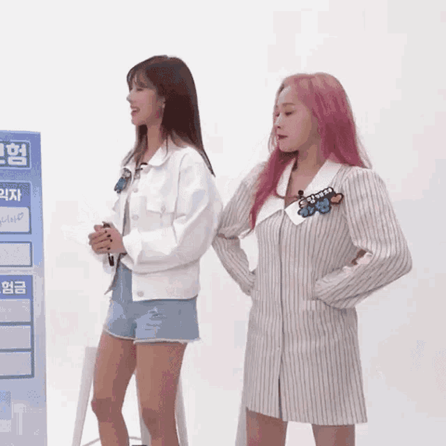 two women with pink hair are standing next to each other .