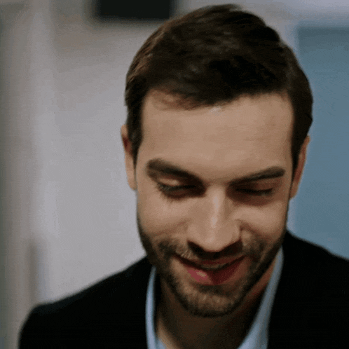 a man with a beard is smiling and looking down