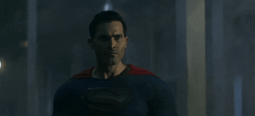 a man in a superman costume is standing in a dark room