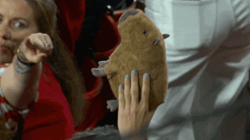 a woman with blue nails holds a stuffed animal in her hand