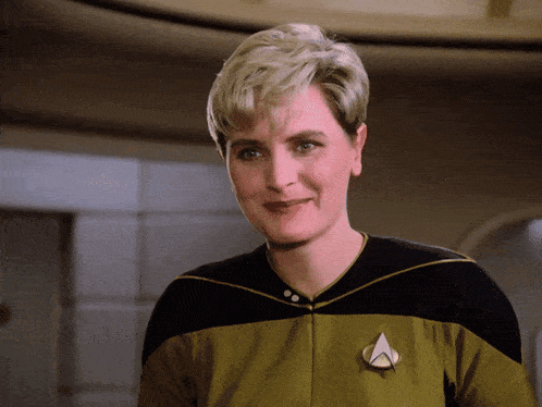 a woman in a star trek uniform has a badge on her chest that says a