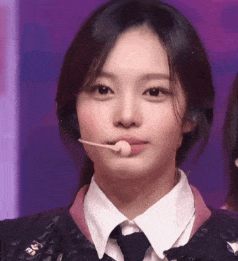 a close up of a woman wearing a tie and a microphone in her mouth .