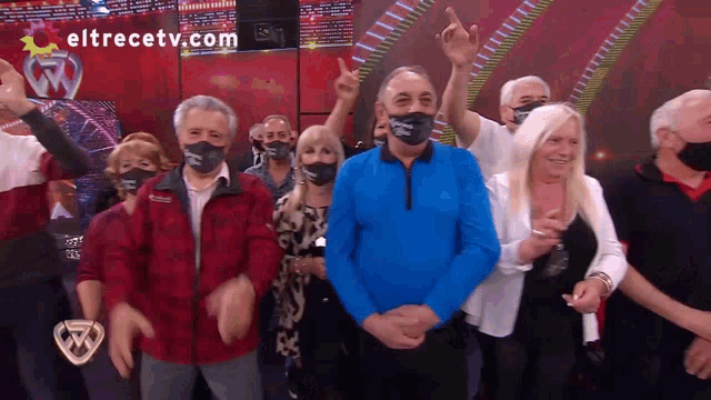a group of people wearing face masks are standing in front of a screen that says eltrecetv.com