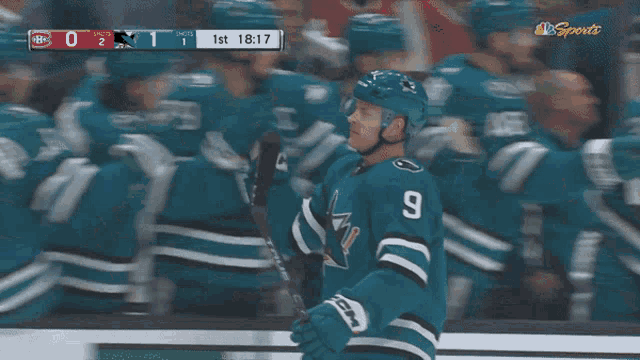 a hockey player with the number 9 on his jersey stands in front of his teammates