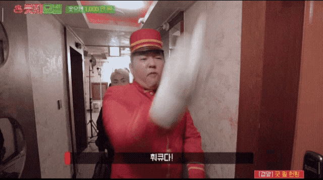 a man in a red uniform is standing in a hallway with chinese writing on the wall