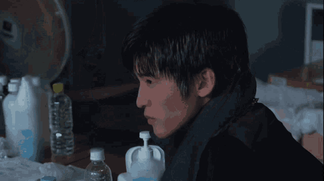 a man sitting at a table with bottles of water and hand sanitizers