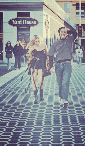 a man and a woman are walking down a street in front of yard house