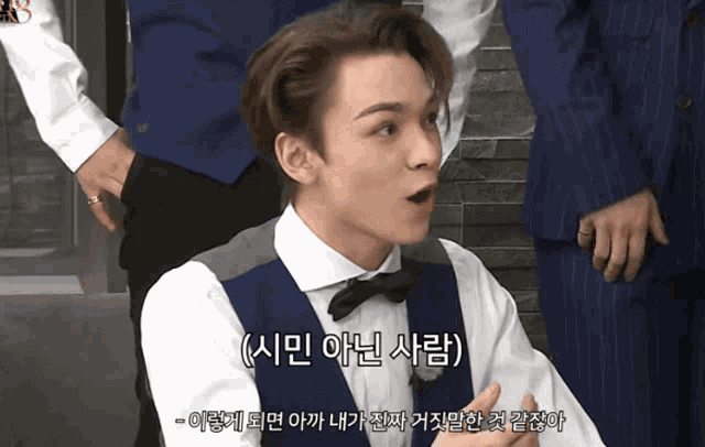 a man in a vest and bow tie is talking in korean