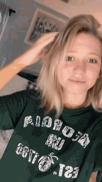 a woman is wearing a green shirt that says aloha