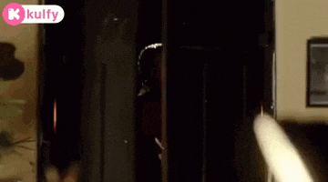 a man is standing in a dark room looking out of a doorway .