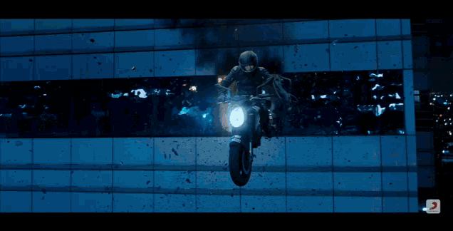 a man is riding a motorcycle in front of a building with a license plate that starts with the letter s
