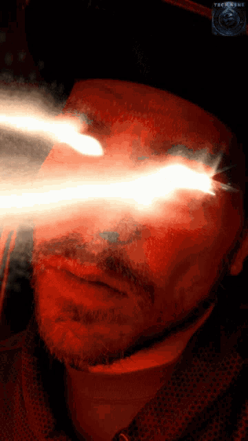 a close up of a man 's face with a red light coming out of his eyes