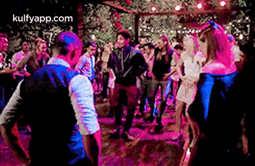 a group of people are dancing at a party in a dark room .