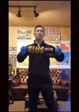 a man is standing in a living room holding a dumbbell in his hand .