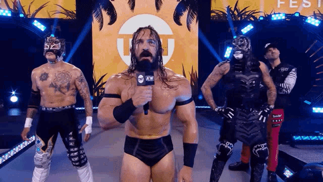 a group of wrestlers are standing on a stage and one of them is holding a microphone
