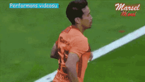 a man in an orange jersey with the number 13 on it is running on a soccer field