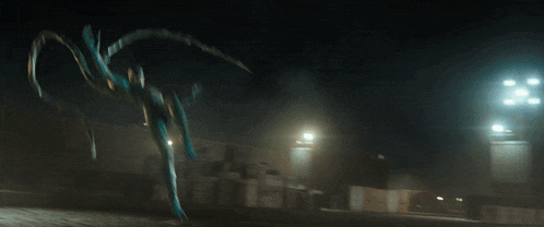 a statue of a person with long arms and legs is standing in the dark