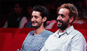 two men are sitting next to each other in a theatre and smiling