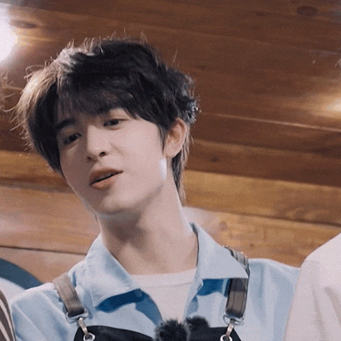 a close up of a young man wearing a blue shirt and overalls