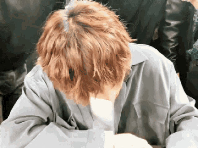 a man with red hair is covering his face with his hands